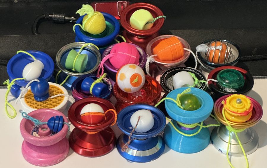 A pile of colorful yo-yos with 5A counterweights tied on, mostly round balls and dice