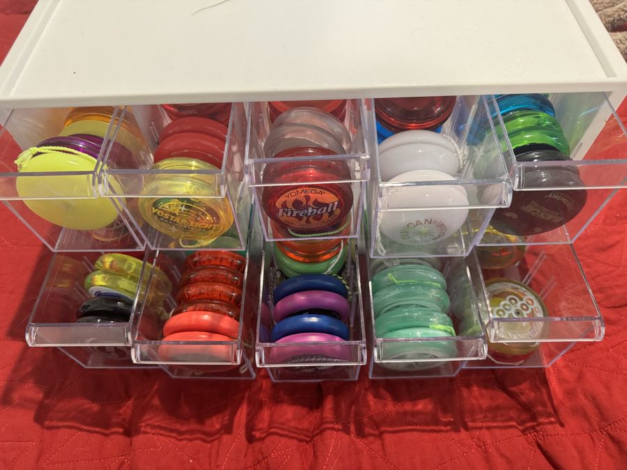 A clear plastic drawer organizer filled with pairs of colorful looping yo-yos