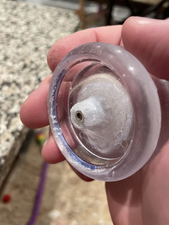 A clear plastic looping yo-yo half with its cap off, the plastic around the axle post cracked