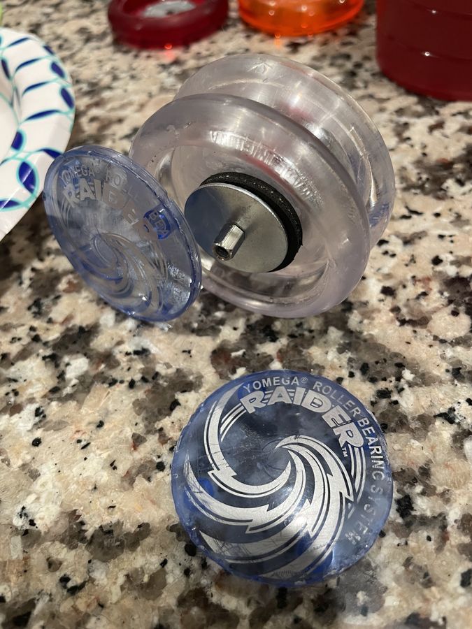 A blue Yomega Raider opened up next to its cap, the post glued back in place with a bearing seated
