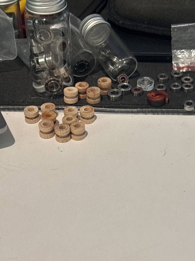 A row of small wooden axle sleeves next to bearings and glass parts tubes