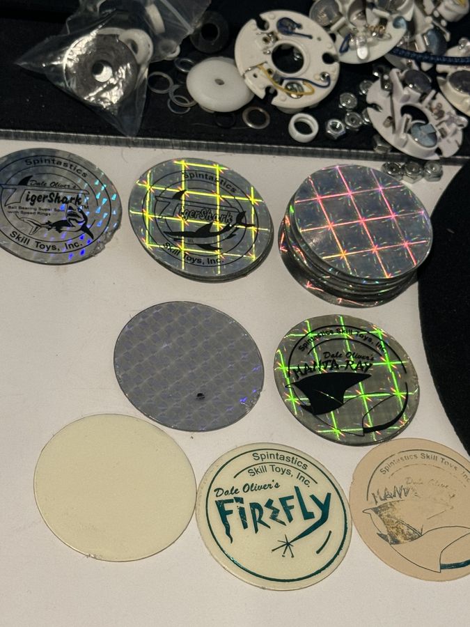 Spintastics cap stickers, pogs, and light-up parts spread out on a desk