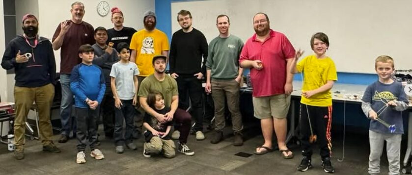 About fifteen DMV Throwers members of all ages posing with yo-yos in a library meeting room