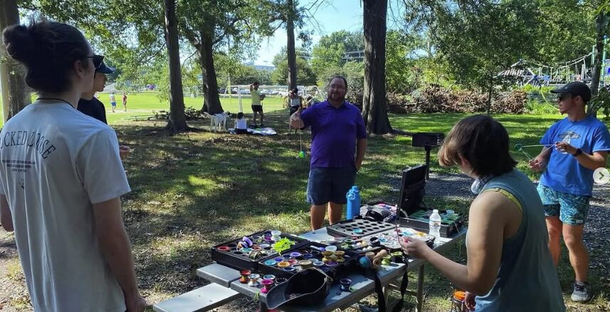 Members trying out yo-yos from a picnic table spread under the trees at Quincy Park
