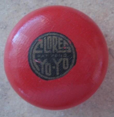 A red wooden yo-yo with a round black Flores Yo-Yo seal