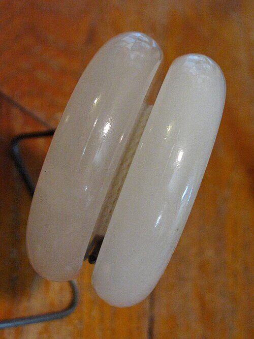 Side profile of a white plastic yo-yo with rounded, slightly flared halves