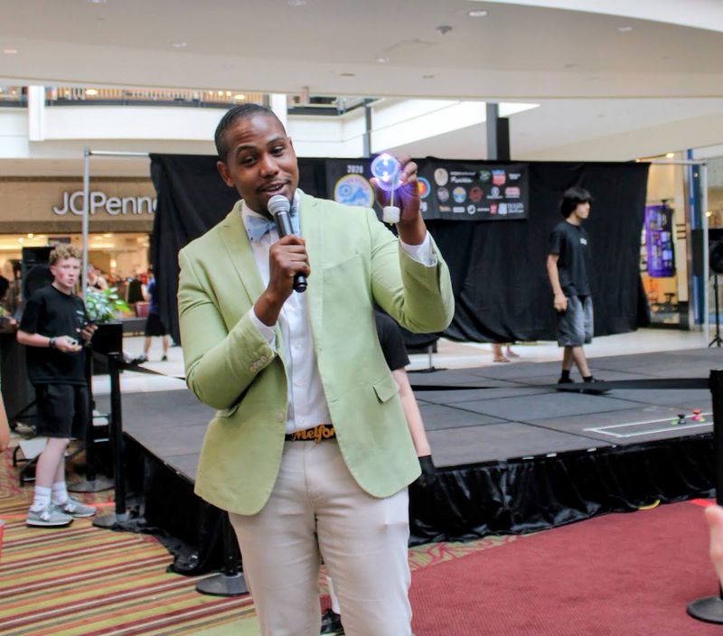 The contest emcee in a light green blazer speaks into a microphone in front of the stage