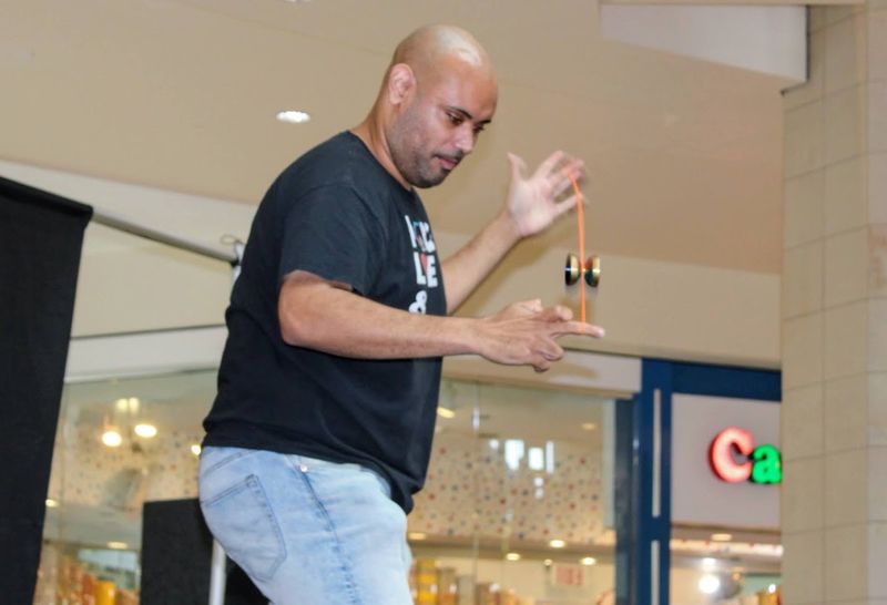 A competitor in a black shirt watches closely as a red yo-yo drops between his hands